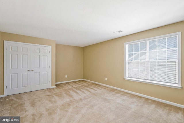 unfurnished bedroom featuring light carpet and a closet