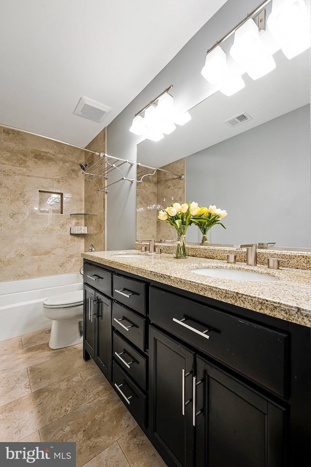 full bathroom featuring tiled shower / bath, vanity, and toilet