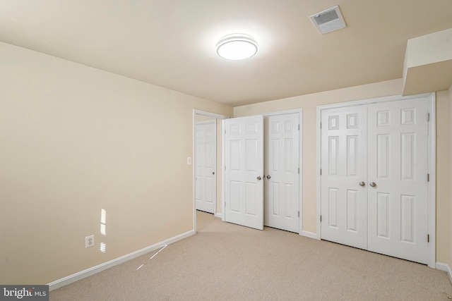 unfurnished bedroom featuring multiple closets and light carpet