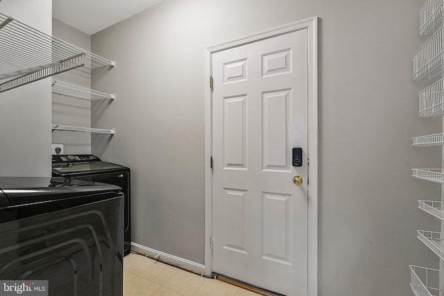 clothes washing area featuring washing machine and dryer and light tile patterned flooring