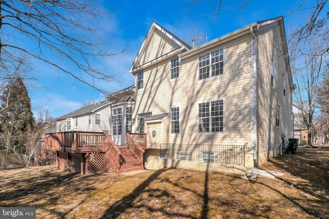 back of property featuring a wooden deck and a lawn