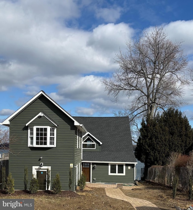 view of front facade featuring fence and a shingled roof