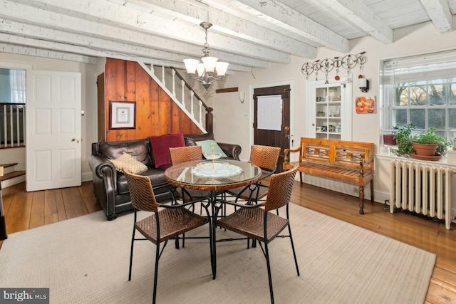 dining area with beamed ceiling, radiator, a chandelier, and light wood-type flooring