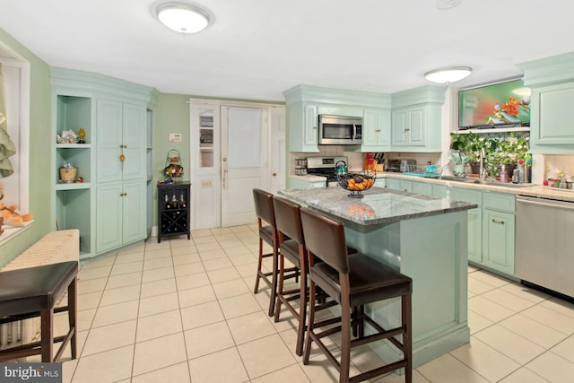 kitchen featuring a center island, stainless steel appliances, a breakfast bar, and light tile patterned flooring