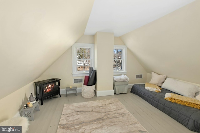 additional living space featuring lofted ceiling, light hardwood / wood-style flooring, and a wood stove