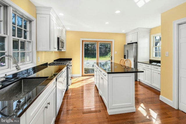 kitchen with white cabinetry, sink, stainless steel appliances, and a kitchen island