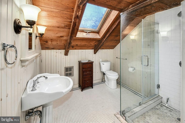 bathroom featuring wooden walls, toilet, vaulted ceiling with skylight, and walk in shower