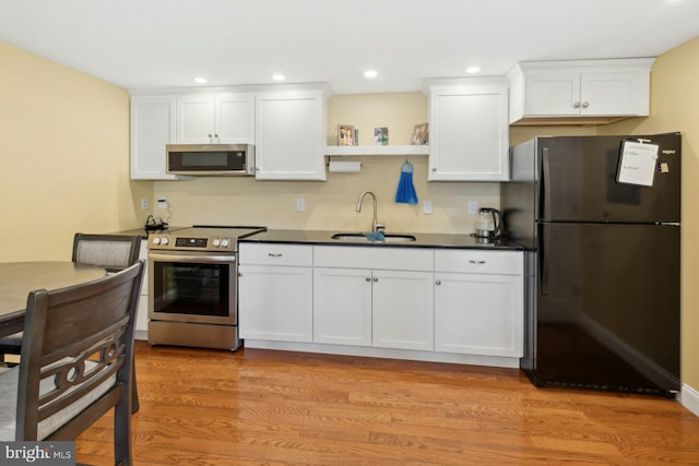 kitchen with white cabinetry, appliances with stainless steel finishes, light hardwood / wood-style floors, and sink