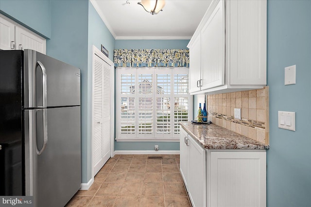 kitchen with baseboards, freestanding refrigerator, ornamental molding, white cabinetry, and backsplash