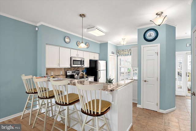 kitchen with tasteful backsplash, a breakfast bar area, appliances with stainless steel finishes, a peninsula, and white cabinets