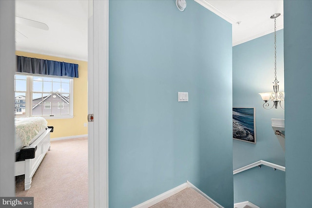 hall with a notable chandelier, baseboards, carpet floors, and ornamental molding