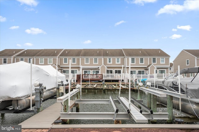 dock area with boat lift, a residential view, and a water view