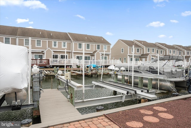 view of dock with a residential view, a water view, and boat lift