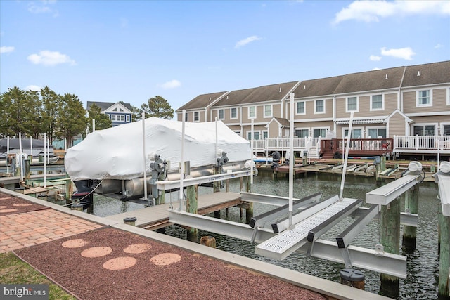 view of dock with a residential view, boat lift, and a water view