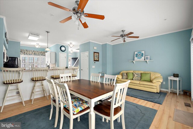 dining area with wood finished floors, a ceiling fan, visible vents, and ornamental molding