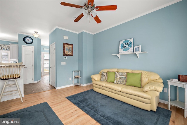 living room with baseboards, crown molding, ceiling fan, and wood finished floors