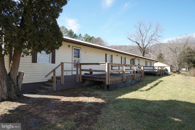 back of property with metal roof, a yard, and a deck