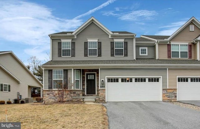 view of front of property with stone siding, aphalt driveway, a front lawn, and an attached garage