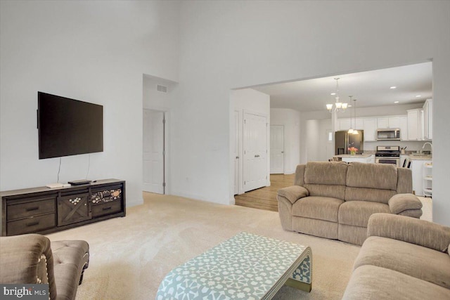 living room with visible vents, light colored carpet, a high ceiling, a notable chandelier, and recessed lighting