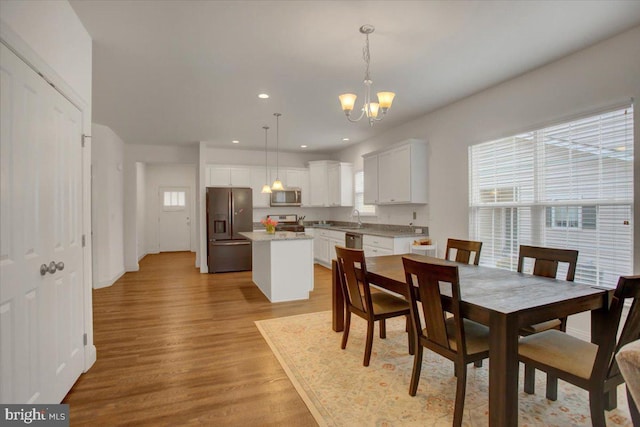 dining area with baseboards, recessed lighting, light wood-type flooring, and a notable chandelier