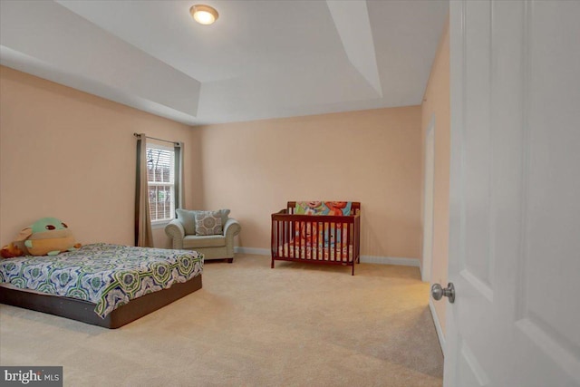 carpeted bedroom featuring a raised ceiling and baseboards