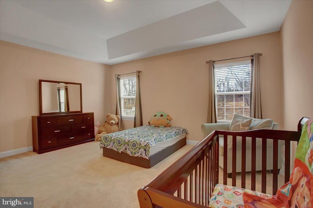 bedroom with carpet, a raised ceiling, and baseboards