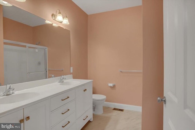 bathroom with double vanity, a shower stall, baseboards, and a sink