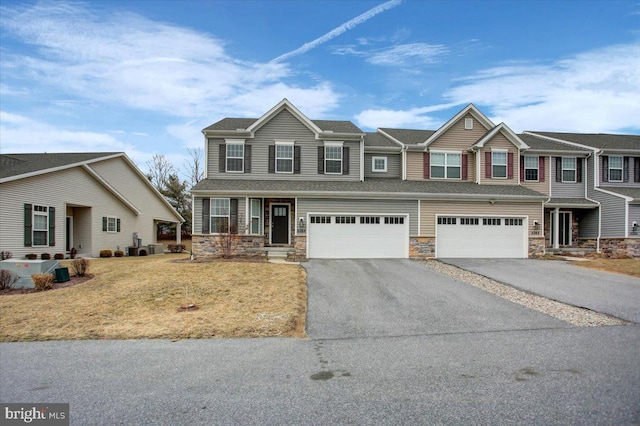 view of front of home featuring driveway, stone siding, a garage, and a front lawn