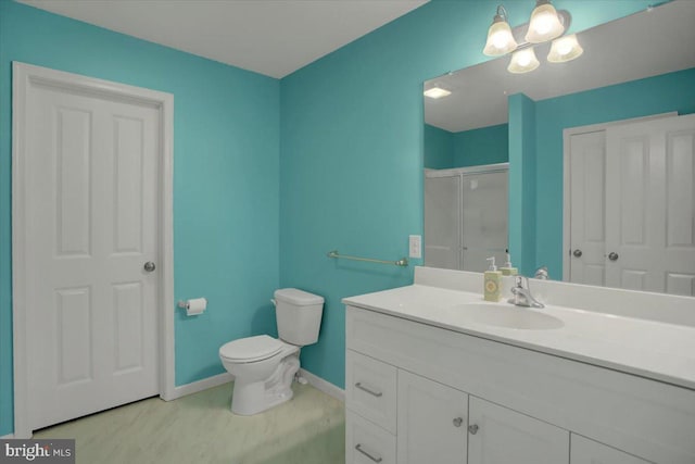 full bathroom featuring toilet, vanity, baseboards, and a shower with shower door