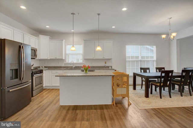 kitchen with light wood-style flooring, white cabinetry, stainless steel appliances, and a sink