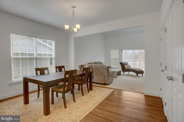 dining space featuring baseboards, a chandelier, and wood finished floors