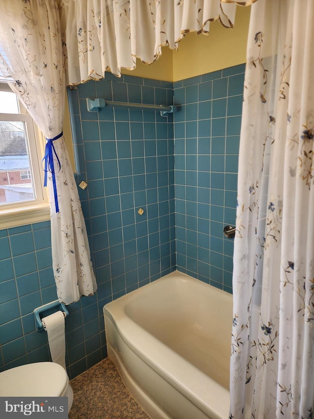 bathroom with shower / bath combo with shower curtain, toilet, and tile walls