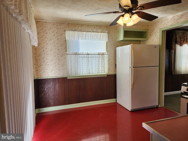 kitchen featuring wood walls, ceiling fan, and white refrigerator