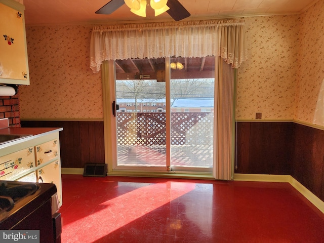 unfurnished dining area featuring crown molding, ceiling fan, and wooden walls