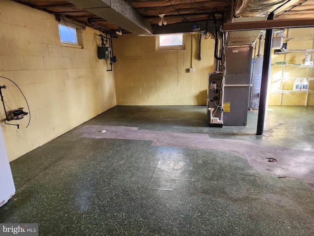 basement featuring water heater, plenty of natural light, and heating unit