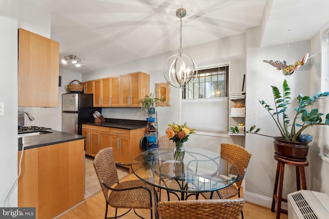 dining room featuring sink, an inviting chandelier, and light wood-type flooring