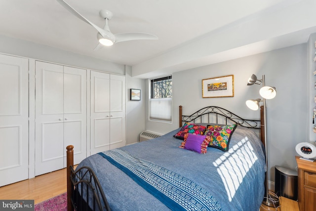 bedroom with ceiling fan, hardwood / wood-style flooring, and multiple closets