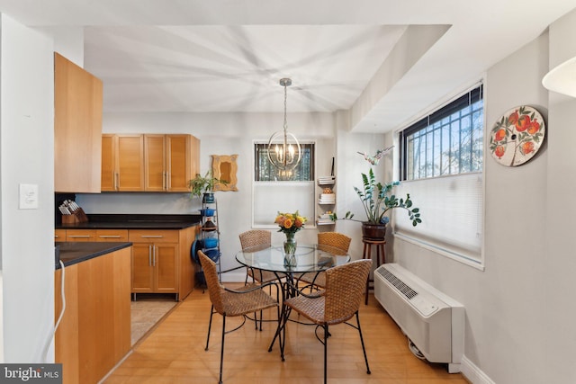 dining space with light hardwood / wood-style floors and an inviting chandelier