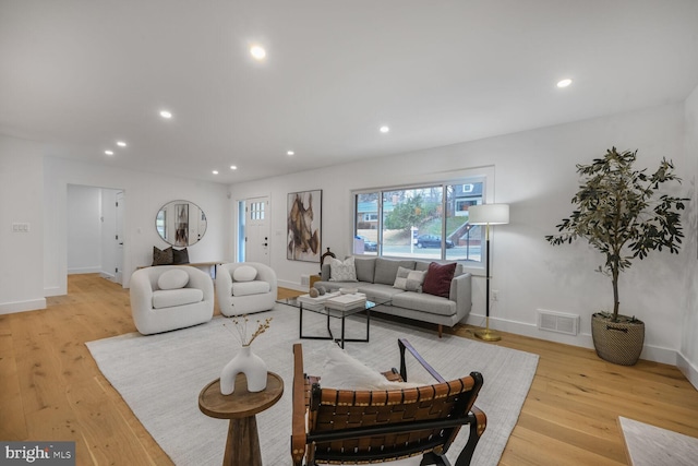 living area featuring baseboards, light wood-type flooring, visible vents, and recessed lighting