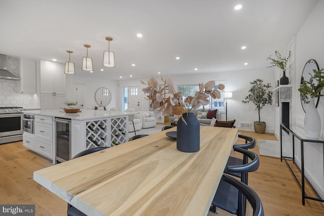 kitchen featuring beverage cooler, white cabinets, hanging light fixtures, and high end stainless steel range