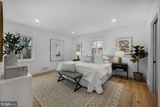 bedroom with baseboards, wood finished floors, visible vents, and recessed lighting