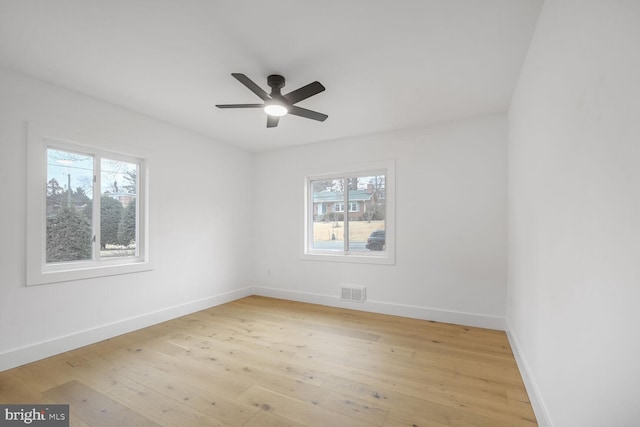 empty room featuring light wood-style flooring, visible vents, baseboards, and ceiling fan