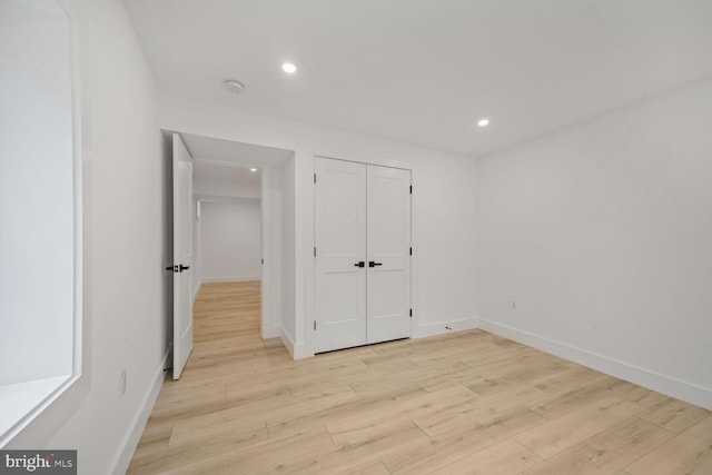 unfurnished bedroom with light wood-type flooring, baseboards, a closet, and recessed lighting