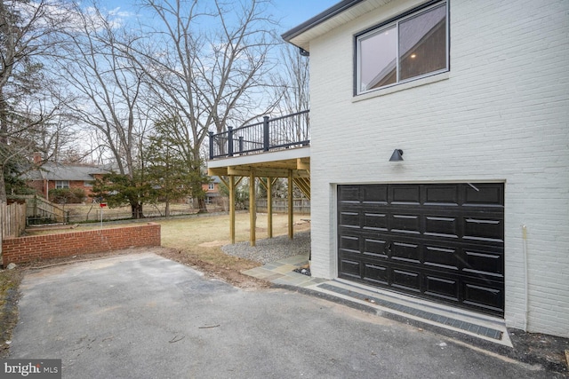 view of side of home featuring a garage, brick siding, a patio, and a deck