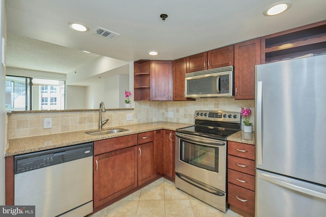 kitchen featuring light tile patterned flooring, sink, light stone counters, appliances with stainless steel finishes, and decorative backsplash