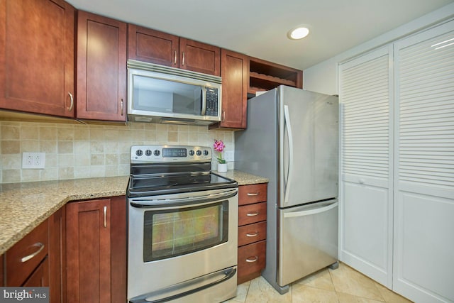 kitchen with tasteful backsplash, stainless steel appliances, light stone countertops, and light tile patterned floors