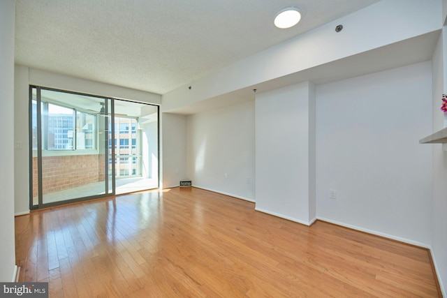 spare room featuring a textured ceiling and light wood-type flooring