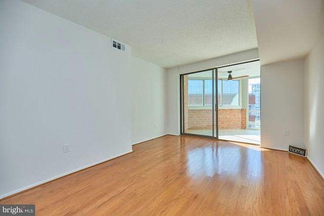 spare room featuring a textured ceiling and light hardwood / wood-style flooring