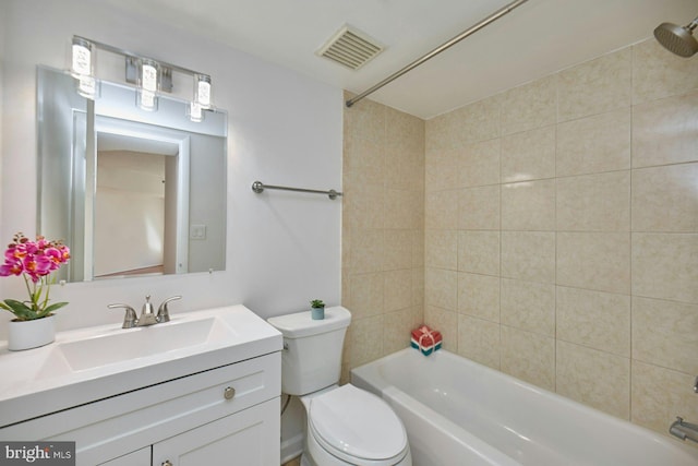 full bathroom featuring vanity, tiled shower / bath combo, and toilet