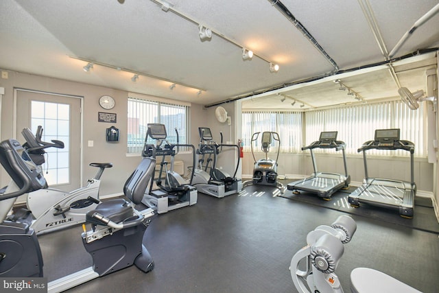 exercise room with track lighting and a textured ceiling